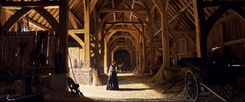 Movie still from “Mary Queen of Scots” (2018), directed by Josie Rourke – A woman standing inside of a barn with hay on the ground; Extreme Wide shot, Low angle