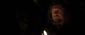 Movie still from “Mary Queen of Scots” (2018), directed by Josie Rourke – A man with long hair and a goatee is holding a lit candle; Close Up shot, Over the shoulder angle