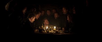 Movie still from “Mary Queen of Scots” (2018), directed by Josie Rourke – A group of men sitting around a table with a lit candle; Medium shot, Over the shoulder angle