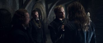 Movie still from “Mary Queen of Scots” (2018), directed by Josie Rourke – A group of men standing next to each other in a room; Medium shot, Over the shoulder angle