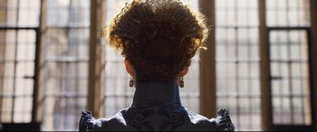 Movie still from “Mary Queen of Scots” (2018), directed by Josie Rourke – The back of a woman's head wearing a dress and earrings; Close Up shot, Over the shoulder angle