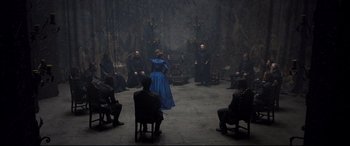 Movie still from “Mary Queen of Scots” (2018), directed by Josie Rourke – A woman in a blue dress is standing in front of a group of people; Wide shot, High angle