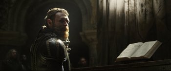 Movie still from “Mary Queen of Scots” (2018), directed by Josie Rourke – A man with a long beard is standing next to a table; Close Up shot, Over the shoulder angle