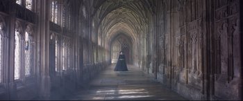 Movie still from “Mary Queen of Scots” (2018), directed by Josie Rourke – A woman in a black dress standing in an archway; Wide shot, High angle