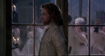 Movie still from “Frankenstein” (1994), directed by Kenneth Branagh – A man standing in front of a window with people in the background; Medium shot, Over the shoulder angle