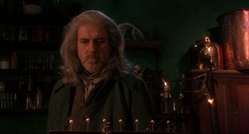 Movie still from “Frankenstein” (1994), directed by Kenneth Branagh – A man with long white hair standing in front of candles; Medium shot, Low angle