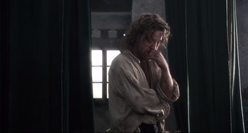 Movie still from “Frankenstein” (1994), directed by Kenneth Branagh – A man with long curly hair leaning on a wall; Medium shot, Low angle
