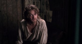 Movie still from “Frankenstein” (1994), directed by Kenneth Branagh – A man with long hair sitting in a room; Medium shot, Over the shoulder angle