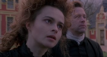 Movie still from “Frankenstein” (1994), directed by Kenneth Branagh – A woman with a curly hair and a man with curly hair in the background; Close Up shot, Low angle