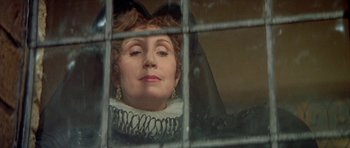 Movie still from “Mary, Queen of Scots” (1971), directed by Charles Jarrott – An older woman looking out of a window through bars; Close Up shot, Over the shoulder angle