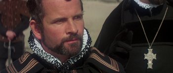 Movie still from “Mary, Queen of Scots” (1971), directed by Charles Jarrott – A man with a beard wearing a black and white collar; Close Up shot, Over the shoulder angle