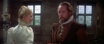 Movie still from “Mary, Queen of Scots” (1971), directed by Charles Jarrott – A man and a woman in medieval garb in front of a brick wall; Medium shot, Over the shoulder angle