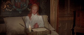 Movie still from “Mary, Queen of Scots” (1971), directed by Charles Jarrott – A woman sitting in a chair next to a lit candle; Medium shot, High angle
