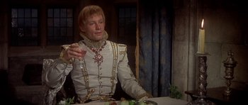 Movie still from “Mary, Queen of Scots” (1971), directed by Charles Jarrott – A man in a suit sitting at a dinner table; Medium shot, Over the shoulder angle