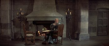 Movie still from “Mary, Queen of Scots” (1971), directed by Charles Jarrott – A woman sitting in front of a fireplace; Wide shot, High angle