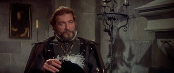 Movie still from “Mary, Queen of Scots” (1971), directed by Charles Jarrott – An older man wearing a black and white outfit; Close Up shot, Over the shoulder angle
