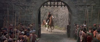 Movie still from “Mary, Queen of Scots” (1971), directed by Charles Jarrott – A man riding a horse through an archway; Wide shot, High angle