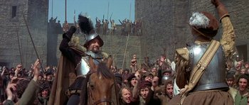 Movie still from “Mary, Queen of Scots” (1971), directed by Charles Jarrott – A crowd of people in medieval garb are gathered around a man on a horse; Wide shot, High angle