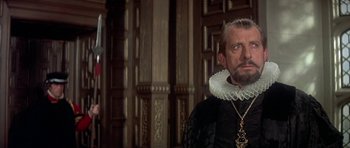 Movie still from “Mary, Queen of Scots” (1971), directed by Charles Jarrott – A person wearing a suit and a necklace; Close Up shot, Over the shoulder angle