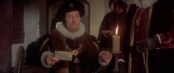Movie still from “Mary, Queen of Scots” (1971), directed by Charles Jarrott – An old man dressed as a renaissance man holding a candle; Medium shot, High angle