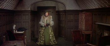 Movie still from “Mary, Queen of Scots” (1971), directed by Charles Jarrott – An older woman dressed in a green and gold dress; Wide shot, High angle