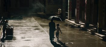 Movie still from “Master Z: The Ip Man Legacy” (2018), directed by Woo-Ping Yuen – A man and a child walking down a street holding an umbrella; Wide shot, High angle