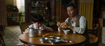 Movie still from “Master Z: The Ip Man Legacy” (2018), directed by Woo-Ping Yuen – A man and a boy sitting at a wooden table; Medium shot, Over the shoulder angle