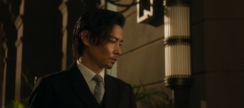 Movie still from “Master Z: The Ip Man Legacy” (2018), directed by Woo-Ping Yuen – A man wearing a suit and tie looking down; Close Up shot, Low angle