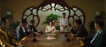 Movie still from “Master Z: The Ip Man Legacy” (2018), directed by Woo-Ping Yuen – A group of people sitting around a wooden table; Medium shot, Low angle