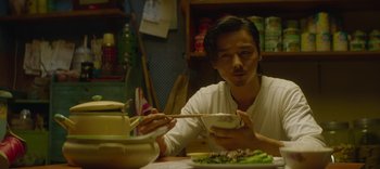 Movie still from “Master Z: The Ip Man Legacy” (2018), directed by Woo-Ping Yuen – A man sitting at a table with a bowl of food in front of him; Close Up shot, Low angle