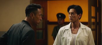 Movie still from “Master Z: The Ip Man Legacy” (2018), directed by Woo-Ping Yuen – Two asian men standing next to each other in front of a building; Close Up shot, Over the shoulder angle