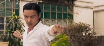 Movie still from “Master Z: The Ip Man Legacy” (2018), directed by Woo-Ping Yuen – A man in a white shirt and black hair is doing a punch; Close Up shot, Low angle