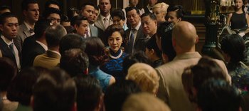 Movie still from “Master Z: The Ip Man Legacy” (2018), directed by Woo-Ping Yuen – A group of people gathered around a woman in a blue dress; Medium shot, Over the shoulder angle