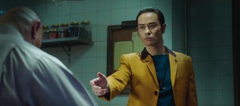 Movie still from “Master Z: The Ip Man Legacy” (2018), directed by Woo-Ping Yuen – A man in a yellow jacket is holding his hand out; Medium shot, Over the shoulder angle
