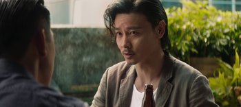 Movie still from “Master Z: The Ip Man Legacy” (2018), directed by Woo-Ping Yuen – A person holding a bottle of beer; Close Up shot, Over the shoulder angle