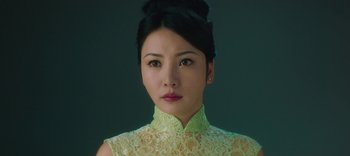Movie still from “Master Z: The Ip Man Legacy” (2018), directed by Woo-Ping Yuen – A woman in a yellow dress is looking at the camera; Close Up shot, Low angle