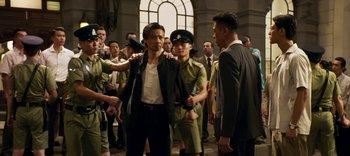 Movie still from “Master Z: The Ip Man Legacy” (2018), directed by Woo-Ping Yuen – A group of men standing next to each other in a room; Medium shot, Over the shoulder angle