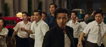 Movie still from “Master Z: The Ip Man Legacy” (2018), directed by Woo-Ping Yuen – A group of men standing next to each other; Medium shot, Over the shoulder angle