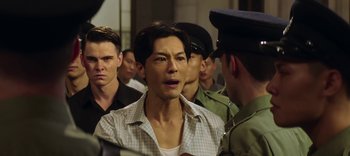 Movie still from “Master Z: The Ip Man Legacy” (2018), directed by Woo-Ping Yuen – A group of men standing around a man in a checkered shirt; Close Up shot, Over the shoulder angle