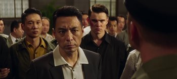 Movie still from “Master Z: The Ip Man Legacy” (2018), directed by Woo-Ping Yuen – A group of men standing next to each other in a room; Close Up shot, Over the shoulder angle