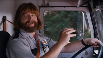 Movie still from “Masterminds” (2015), directed by Jared Hess – A man with long hair and a goatee sitting in a vehicle; Medium shot, Over the shoulder angle
