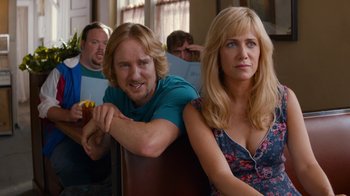 Movie still from “Masterminds” (2015), directed by Jared Hess – A man and a woman sitting next to each other in a room; Close Up shot, Over the shoulder angle