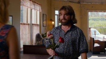 Movie still from “Masterminds” (2015), directed by Jared Hess – A man holding a red rose in his hand; Medium shot, Over the shoulder angle