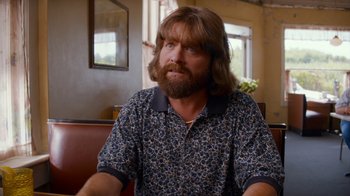 Movie still from “Masterminds” (2015), directed by Jared Hess – A man with long hair and beard sitting at a table; Close Up shot, Over the shoulder angle