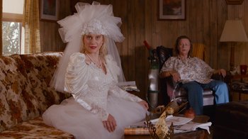 Movie still from “Masterminds” (2015), directed by Jared Hess – A woman in a wedding dress sitting next to another woman in a chair; Medium shot, Over the shoulder angle