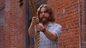 Movie still from “Masterminds” (2015), directed by Jared Hess – A man holding on to a long rope; Medium shot, Low angle