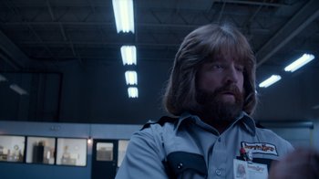 Movie still from “Masterminds” (2015), directed by Jared Hess – A man with long hair and a beard wearing a police uniform; Close Up shot, Over the shoulder angle