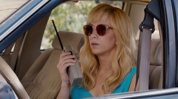 Movie still from “Masterminds” (2015), directed by Jared Hess – A woman sitting in the back of a car holding a cell phone; Close Up shot, High angle