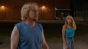 Movie still from “Masterminds” (2015), directed by Jared Hess – A man and a woman standing next to each other in a field; Medium shot, Over the shoulder angle