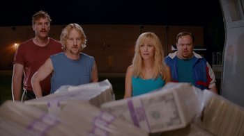 Movie still from “Masterminds” (2015), directed by Jared Hess – A group of people standing next to a pile of money; Medium shot, Over the shoulder angle